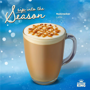 Nutcracker Latte in a clear mug with a blue background and 'Coffee King' branding.