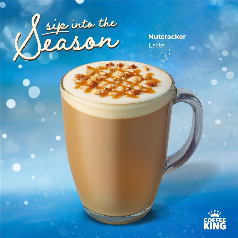 Nutcracker Latte in a clear mug with a blue background and 'Coffee King' branding.