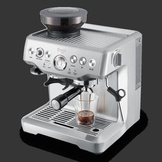 Sage espresso machine with a glass of coffee on a black background