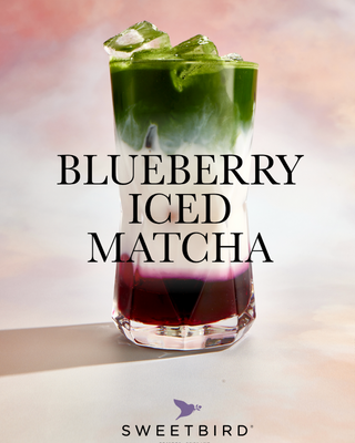 Blueberry iced matcha drink with ice cubes in a glass, branded 'Sweetbird'.