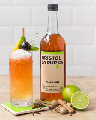 Bottle of Bristol Syrup Co. Falernum with a cherry falernum cooler and ingredients.