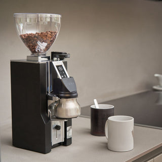 Eureka Mignon Libra 65 All Purpose coffee grinder on a kitchen counter beside two coffee mugs