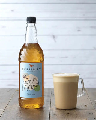 Bottle of Sweetbird Sugar Free Hazelnut Syrup and a glass of sugar free hazelnut latte.